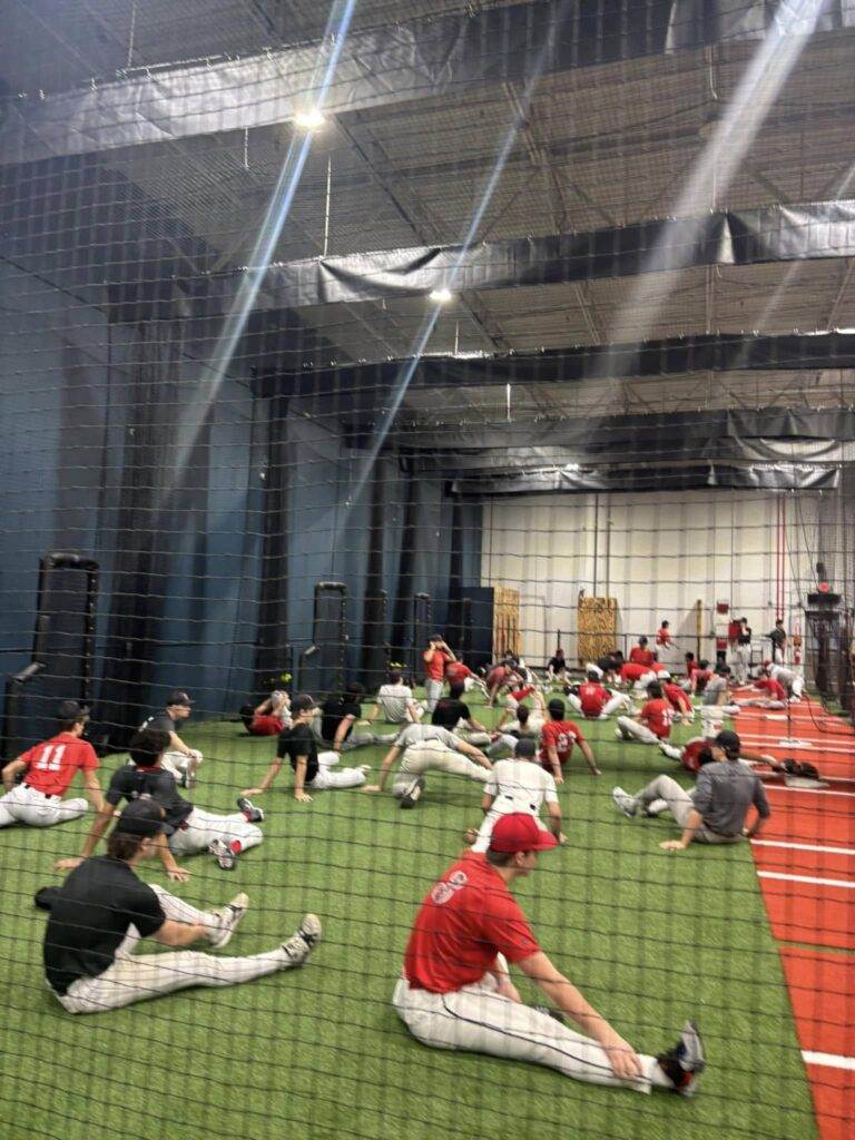 Teen baseball player stretching inside the batting cages