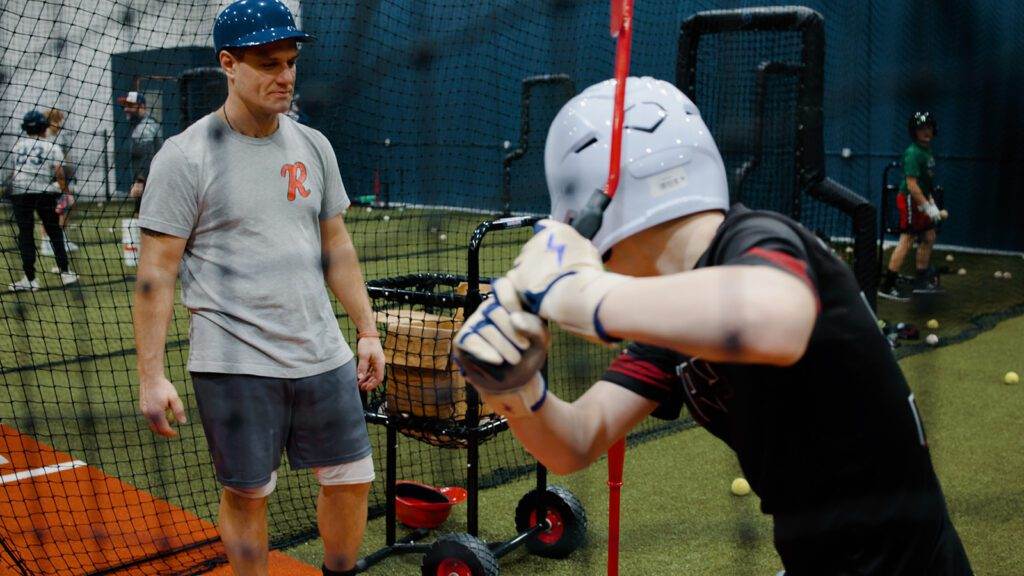 Coach Sammy is showing a player how to grip a bat