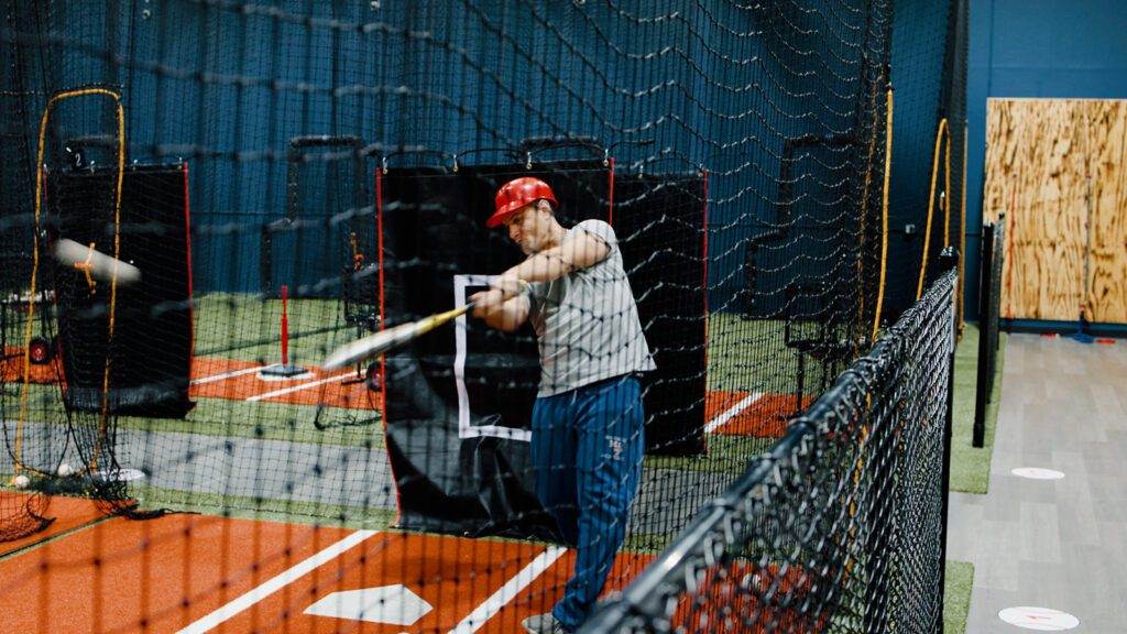 Coach Sammy is demonstrating a swing in the batting cages