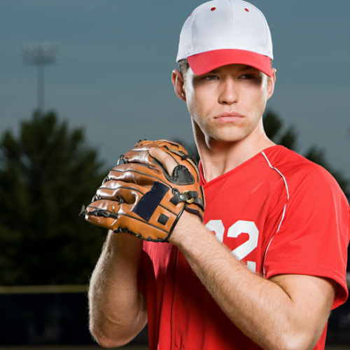 A young male baseball player in a white hat and red jersey